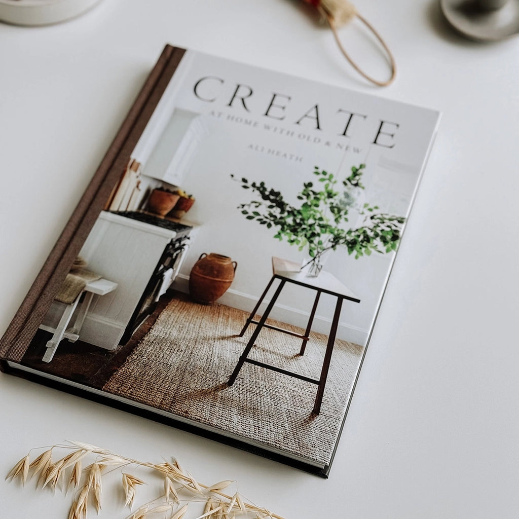 The book, Create: At Home with Old & New, is elegantly displayed on a table in a photograph, offering a glimpse of its pages teeming with innovative interior design inspirations.