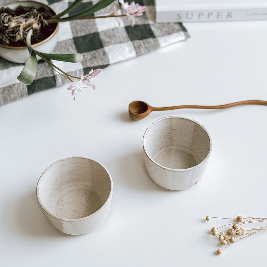A pair of stoneware bowls with an almond white glaze, byFoke.