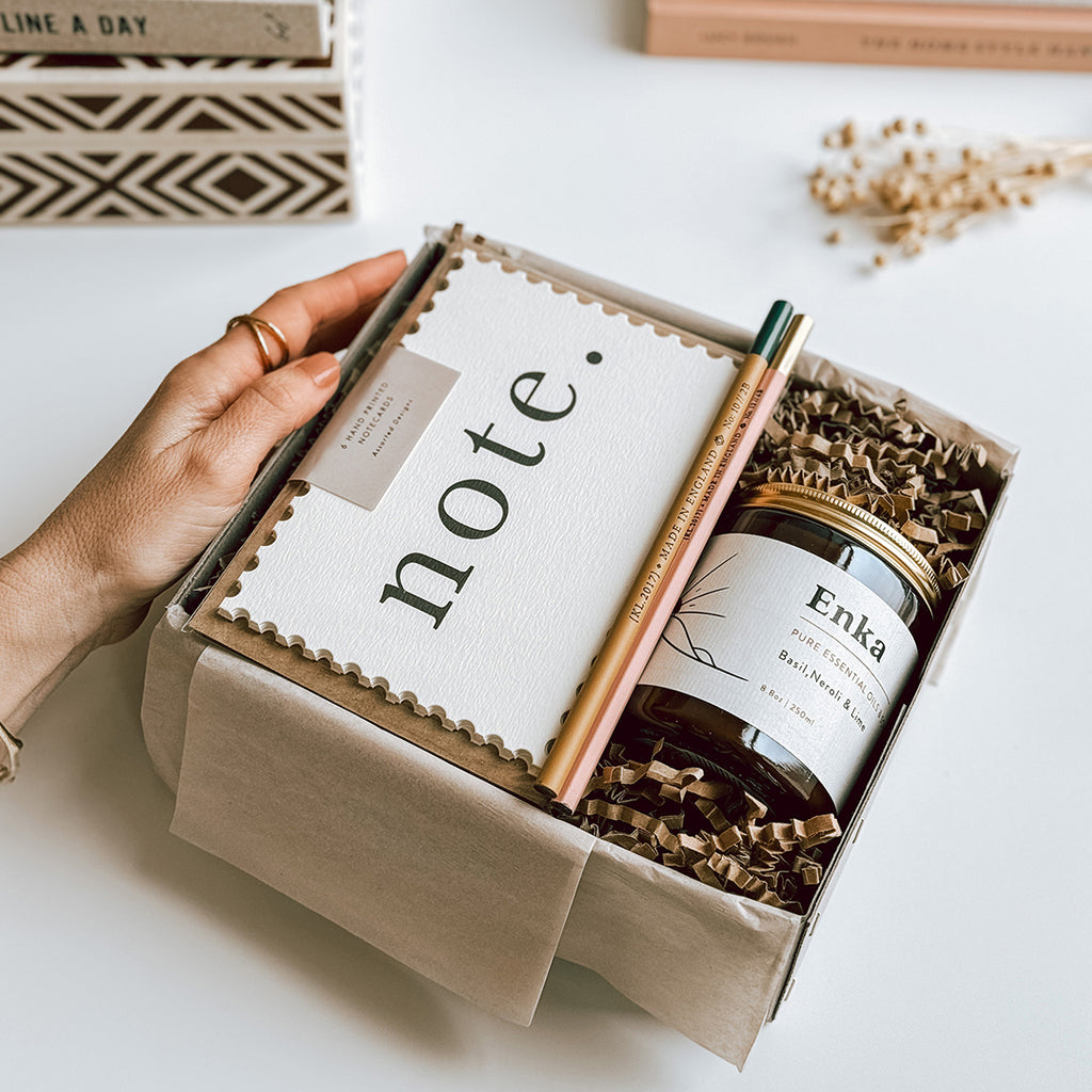 The byFoke Kaisa Notecard and candle gift set, open on a table containing Katie Leamon Notecard Set, 2 pencils and a byFoke essential oil soy wax candle.