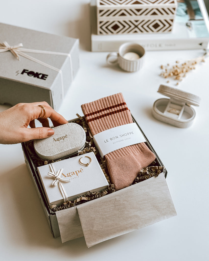 byFoke Mother's Day Gift Box, including a gold knot ring by Agape Studio, a linen travel jewellery box and a pair of Le Bon Shoppe Boyfriend socks. The box is lying open on a table, showing it's contents, the lid lies to the side wrapped in ribbon.