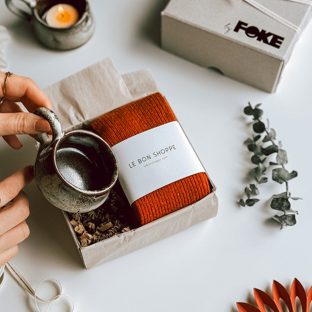 An open byFoke Gift Box with a pair of Le Bon Shoppe Snow Socks in Gingerbread and a stoneware candle holder.