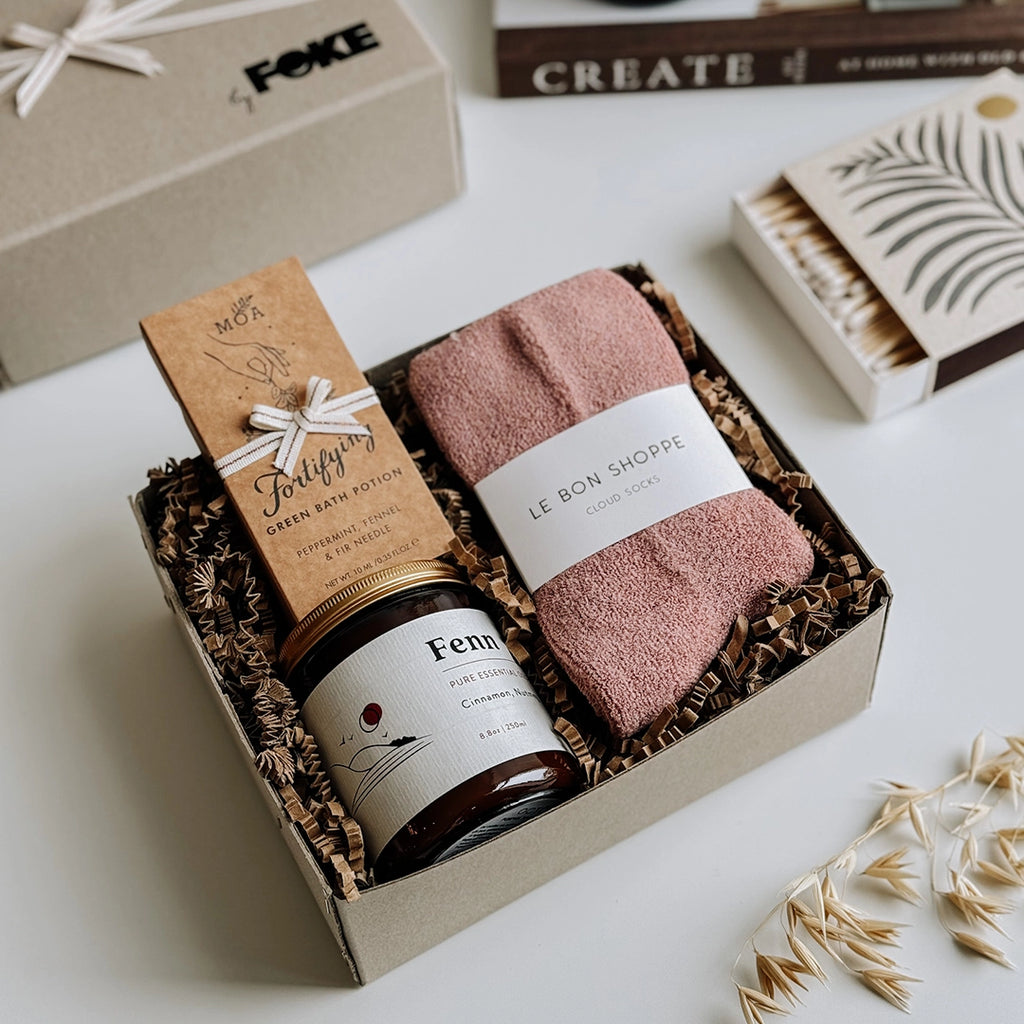 The Perdy Gift Box byFoke laying open on a table. The gift box contains; Cloud Socks by Le Bon Shoppe in Mulberry, Fenn Essential Oil Soy Wax Candle, Fortifying Green Bath Potion by MOA
