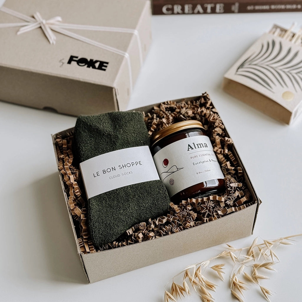 byFoke's Chloe Gift Box, opened with the lid to one side. Inside the gift box is a pair of dark green cloud socks and an Alma essential oil candle.