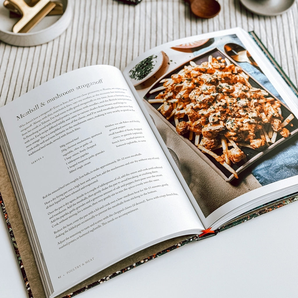 In the picture, "Persiana Everyday" by Sabrina Ghayour is displayed open on the table, featuring the meatball and mushroom stroganoff recipe.