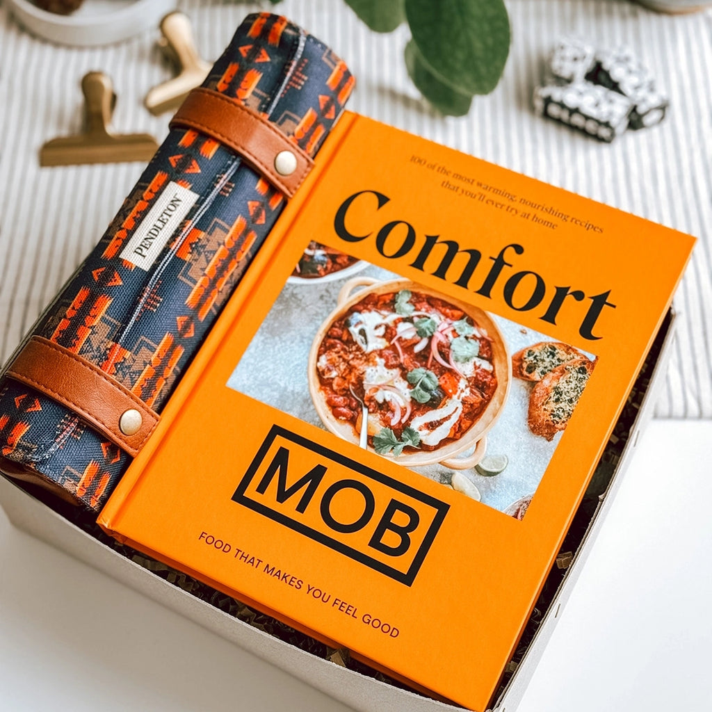 The Lev Gift Box byFoke laying open on a kitchen table, inside is the Comfort MOB cook book and a Pendleton Chess Set.