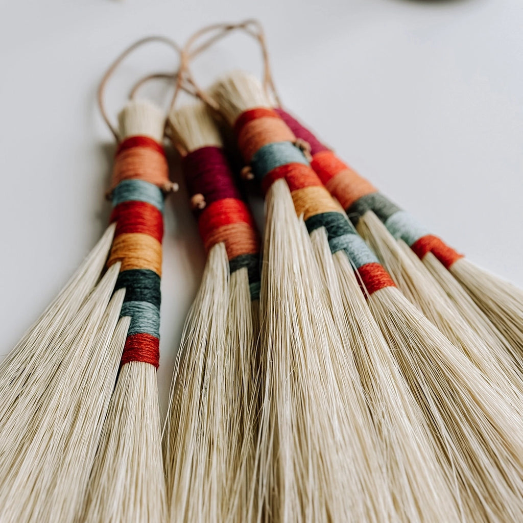 A close up of the coloured woollen handles of the Twig Stick Tampico brushes.