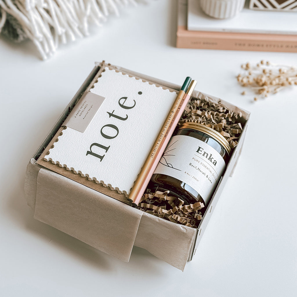 Kaisa Gift Box byFoke, open on a table containing Katie Leamon Notecard Set, 2 pencils and a byFoke essential oil soy wax candle.