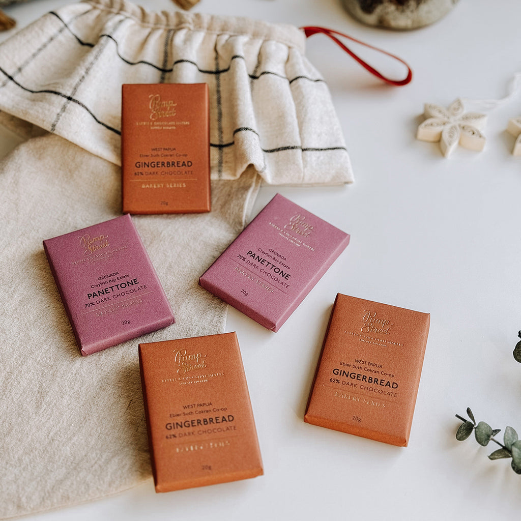 A collection of Pump Street Panettone & Gingerbread Chocolate Bars laying on a table with a byFoke Christmas Stocking.