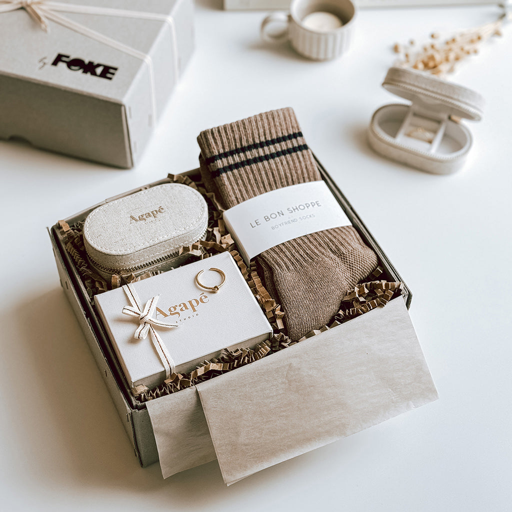 byFoke's Romy Luxury Gift Box laying open on a table with the lid in the background. Inside you can see an Agape gold ring, linen jewellery box and a pair of Le Bon Shoppe socks in Cocoa.