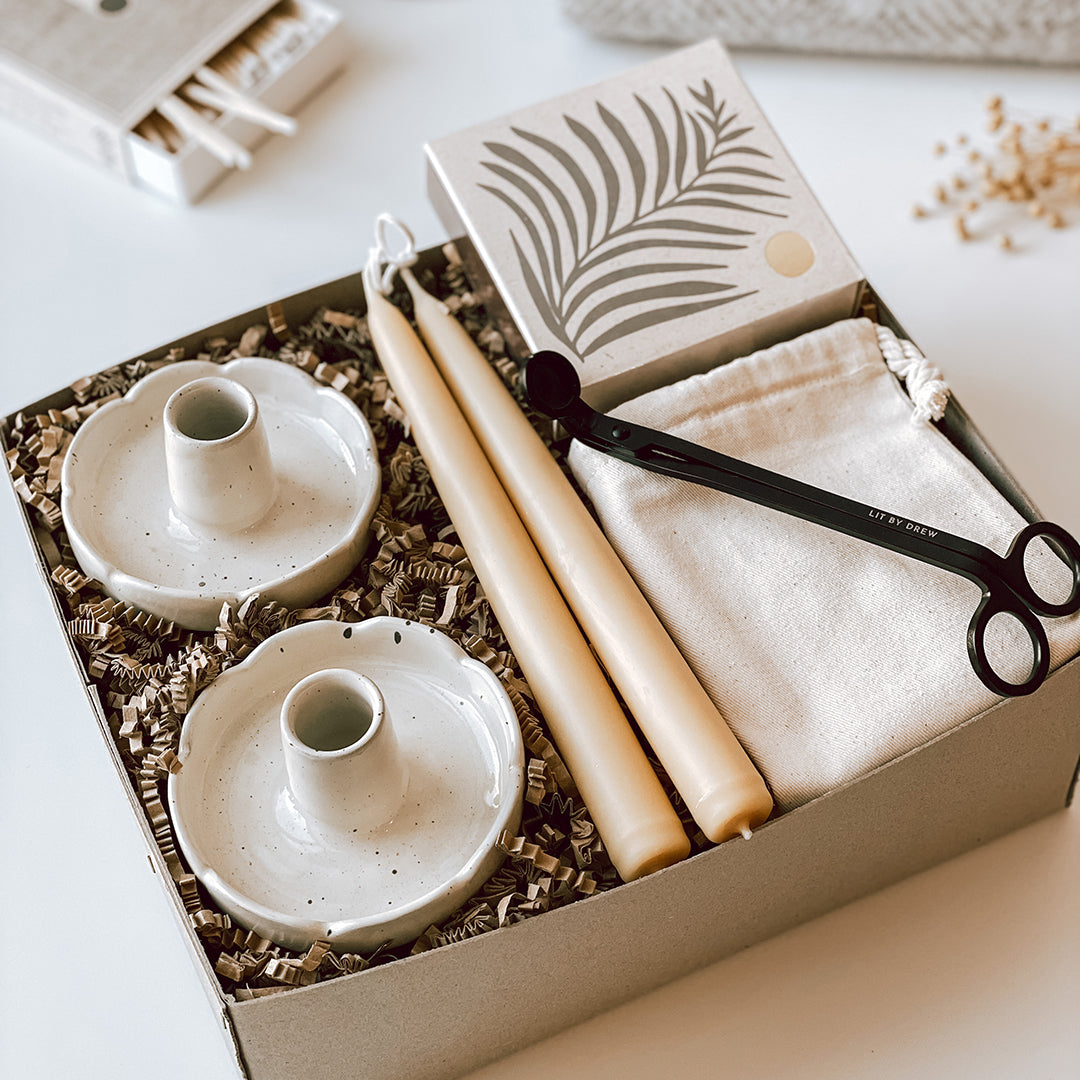 An open byFoke Cora gift box containing a set of two stoneware flower candle holders, a pair of beeswax taper candles, luxury letterpress matches by Archivist and a pair of candle wick trimmers.