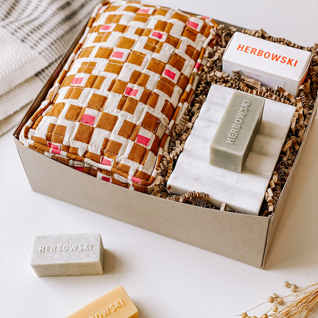 Ingrid bath and body gift box byFoke containing a block-printed wash bag with a pink and rust coloured pattern, Herbowski soap bar and a marble soap dish.