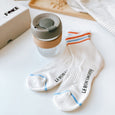 A pair of stripy Le Bon Shoppe Girlfriend socks and a glass KeepCup with a khaki lid, laying in front of a byFoke gift box.
